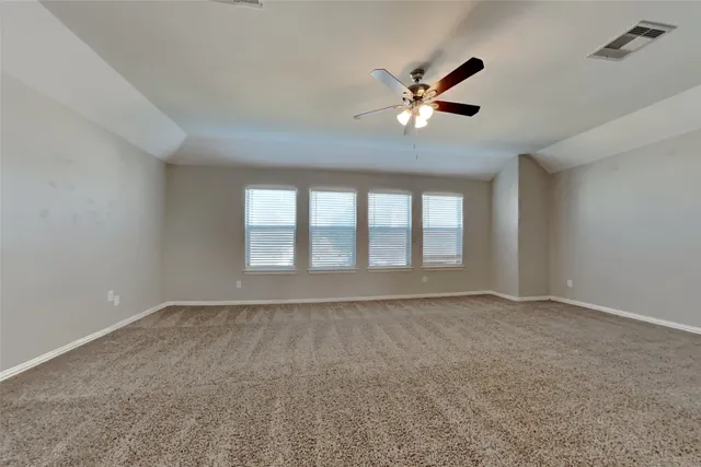 a view of an empty room with window and chandelier fan