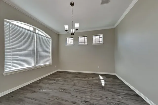 a view of empty room with wooden floor and window