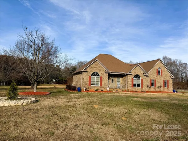 a front view of a house with a yard covered with trees