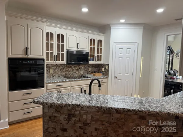 a hall with stainless steel appliances granite countertop a stove a sink and a microwave
