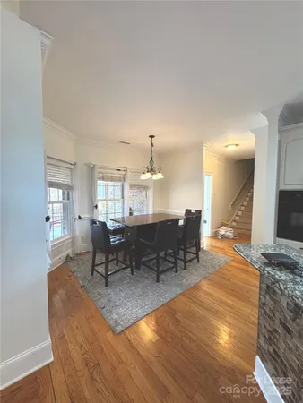 a dining room with wooden floor a chandelier a wooden table and chairs