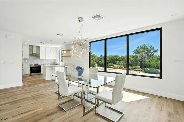 a dining room with wooden floor a chandelier a glass table and chairs