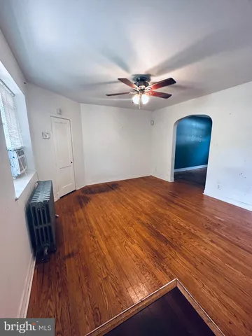 a view of an empty room with a chandelier fan and wooden floor
