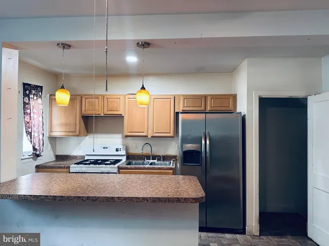 a view of kitchen and empty room with wooden floor