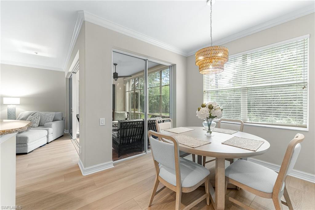 817 Carrick Bend Circle, Unit 102 Naples, FL 34110 - Photo 14 of 36 Dining room with light wood-style flooring, ornamental molding, and a chandelier