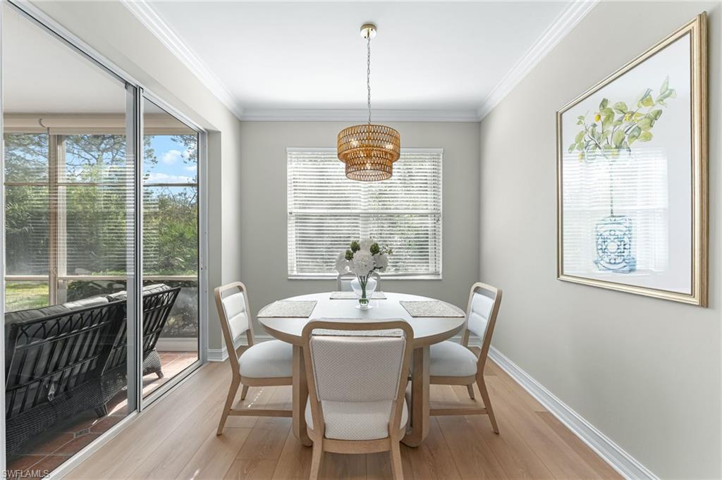 817 Carrick Bend Circle, Unit 102 Naples, FL 34110 - Photo 15 of 36 Dining space with crown molding, wood-type flooring, and a chandelier