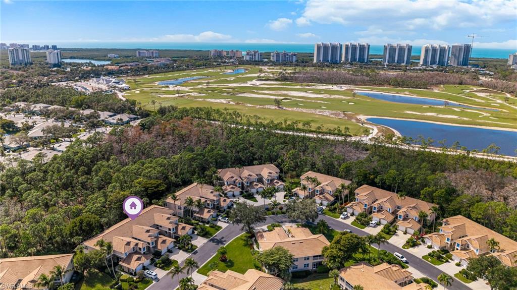 817 Carrick Bend Circle, Unit 102 Naples, FL 34110 - Photo 27 of 36 Aerial view of property and surrounding area with a nearby body of water, a golf course, and nearby suburban area