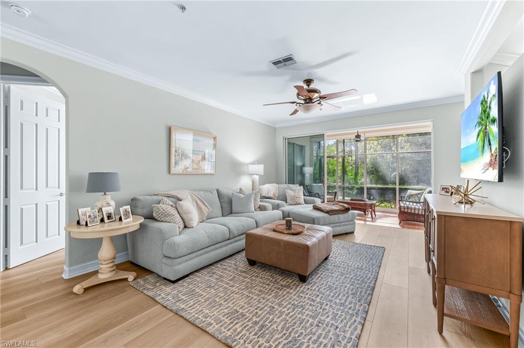 817 Carrick Bend Circle, Unit 102 Naples, FL 34110 - Photo 5 of 36 Living room featuring ornamental molding, light wood-style flooring, a ceiling fan, and arched walkways