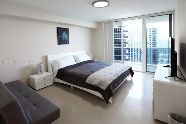 a spacious bedroom with a bed and a flat tv screen next to a window