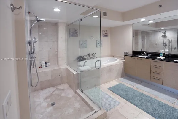 a bathroom with a tub a sink a mirror and a shower