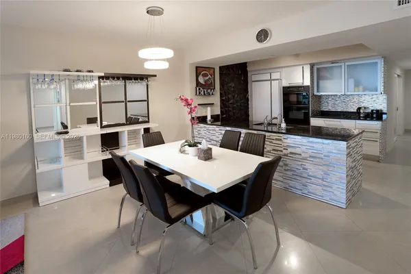 a dining area with a table chairs and a kitchen view