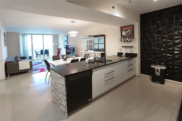 a kitchen with stainless steel appliances granite countertop a sink dishwasher a stove and a dining table with wooden floor