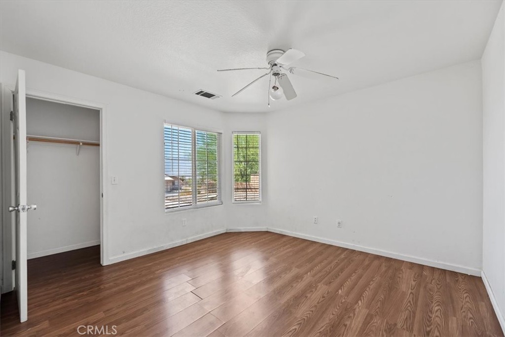 66034 Santa Rosa Road Desert Hot Springs, CA 92240 - Photo 28 of 54 an empty room with wooden floor chandelier fan and windows