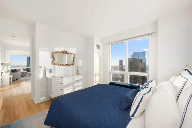 a spacious bedroom with a bed a couch and large window