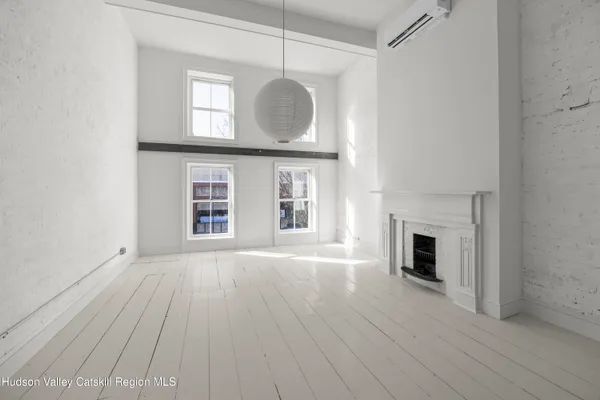 a view of an empty room with wooden floor fireplace and a window