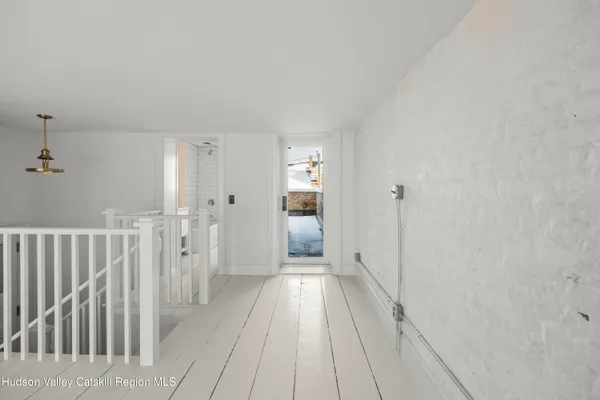 a view of a hallway with wooden floor and a bathroom