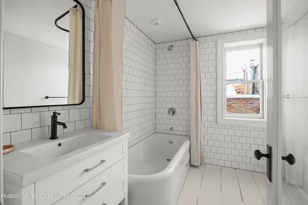 a bathroom with a tub a sink and mirror