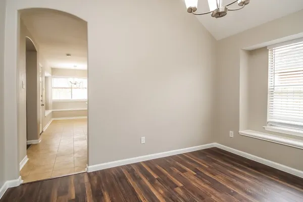 an empty room with wooden floor cabinet and windows