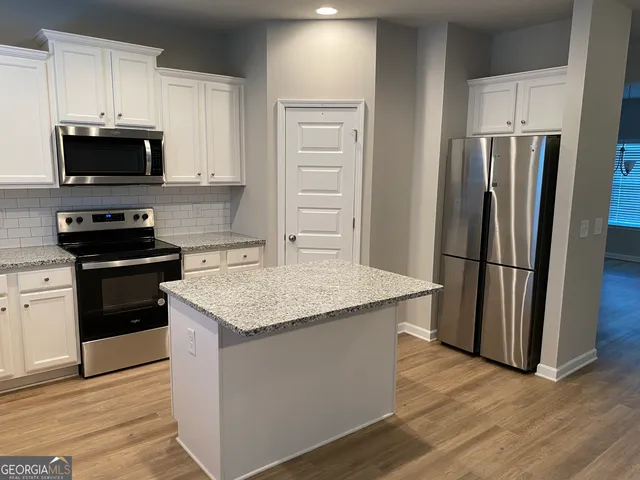 a kitchen with stainless steel appliances kitchen island granite countertop a refrigerator stove and microwave