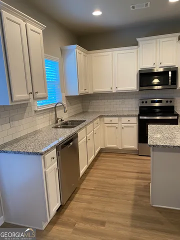 a kitchen with stainless steel appliances granite countertop a sink stove and cabinets