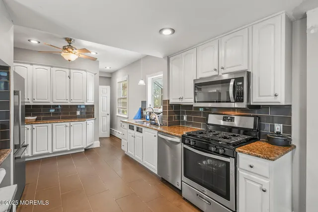 a kitchen with granite countertop white cabinets and stainless steel appliances