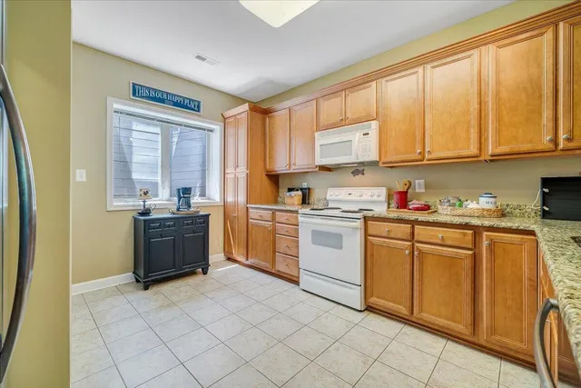 a kitchen with stainless steel appliances granite countertop a refrigerator a sink dishwasher and white cabinets with wooden floor