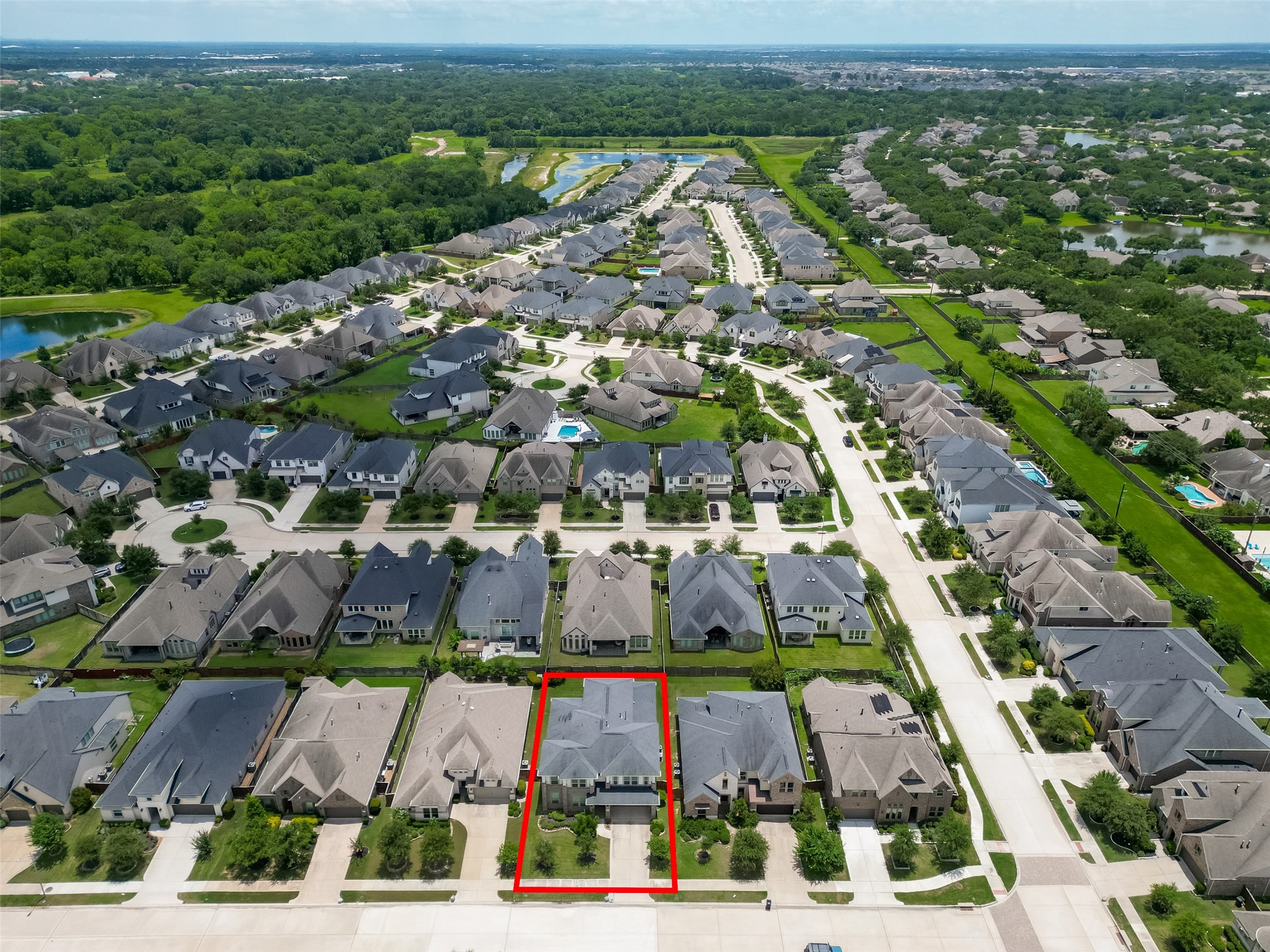 1815 Brea Rdg Trail Katy, TX 77494 - Photo 39 of 43 This aerial photo showcases a suburban neighborhood with neatly arranged houses, each with a driveway and green lawns. The highlighted property is centrally located on a quiet street, surrounded by similar homes. The area features ample greenery and is close to a wooded landscape, offering a tranquil setting.