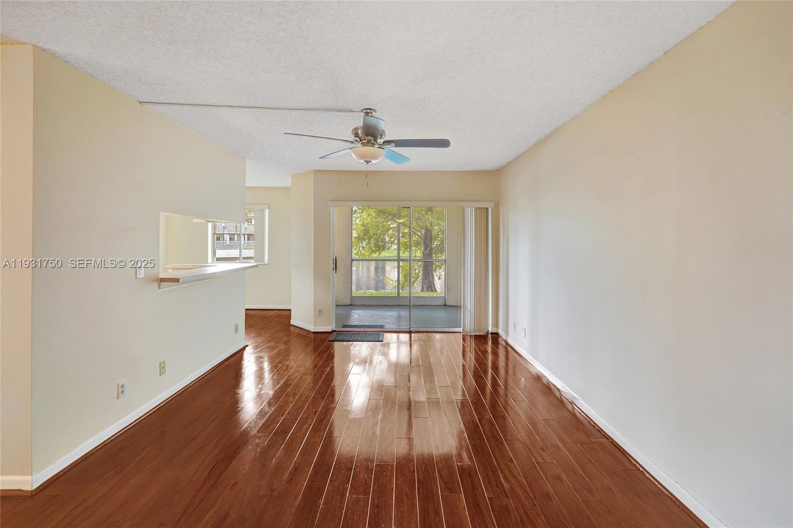 9833 Westview Drive, Unit 819 Coral Springs, FL 33076 - Photo 9 of 47 an empty room with wooden floor chandelier fan and windows