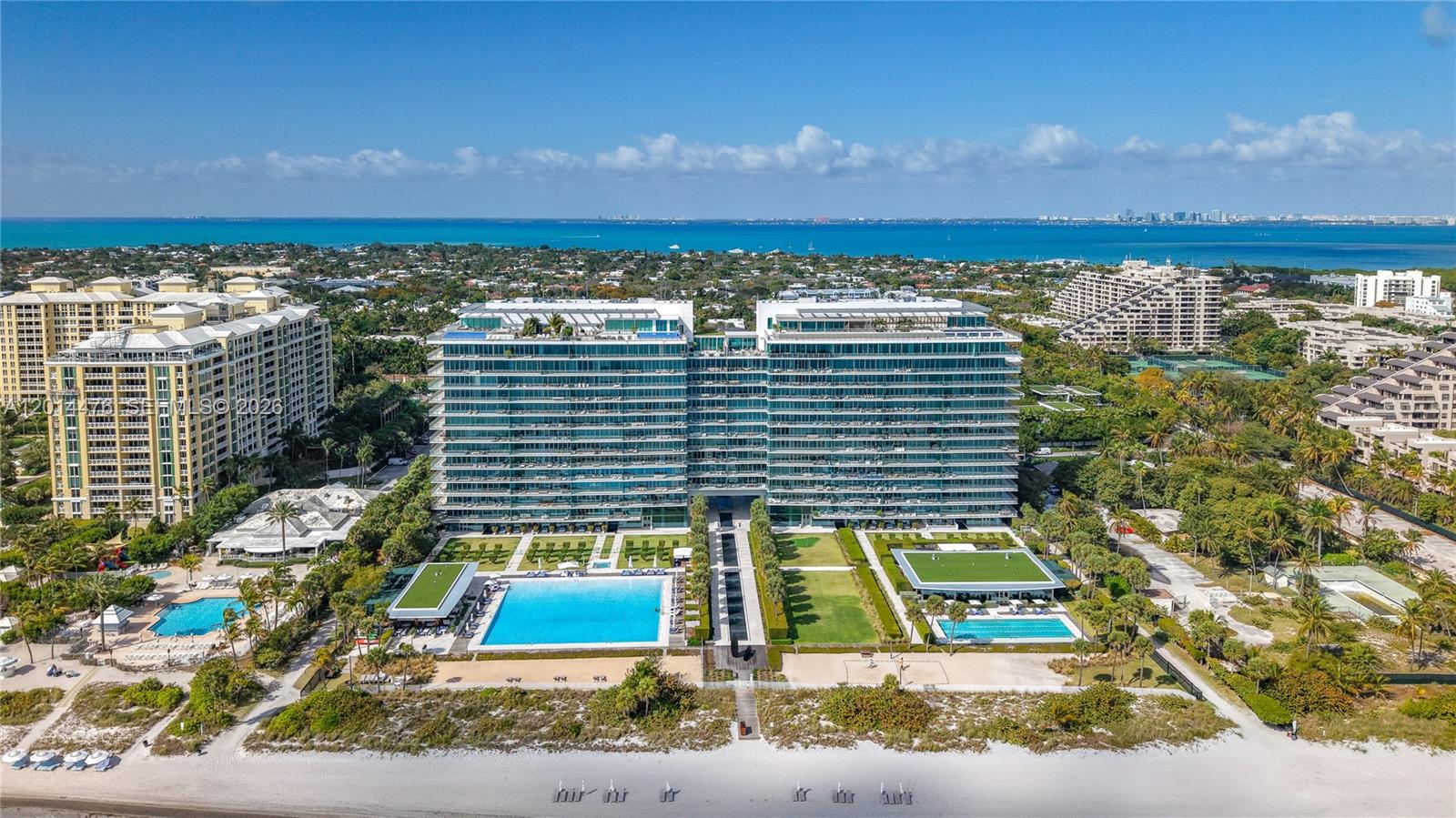 Full Exterior / Beachfront Overview – A broad exterior view presents the full building, landscaped grounds, resort-style pools, and direct beachfront frontage. The composition offers a complete look at the property’s oceanfront setting and amenity-rich surroundings.