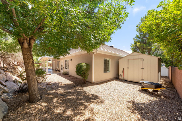 621 East 940 South St. George, UT 84790 - Photo 51 of 55 Spacious backyard featuring gravel landscaping, mature trees, a detached storage shed, a covered patio, and a stucco exterior