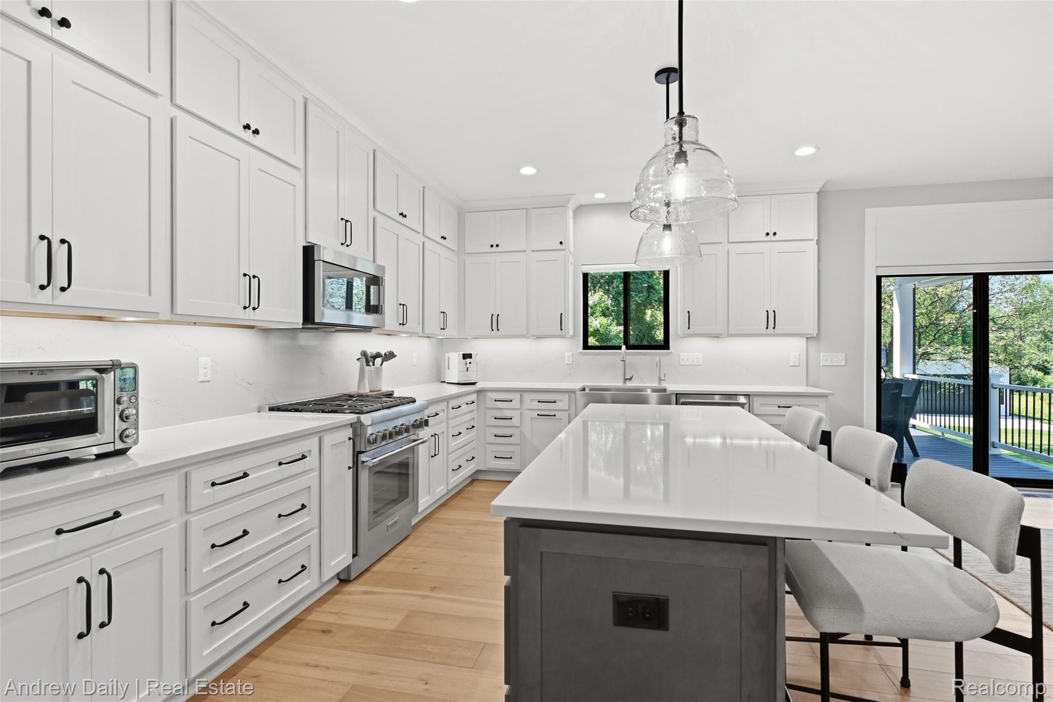 4661 Spears Road Pinckney, MI 48169 - Photo 23 of 56 Modern kitchen featuring white shaker-style cabinetry, stainless steel appliances, light-finish flooring, a central island with countertop seating, and clear glass pendant lighting