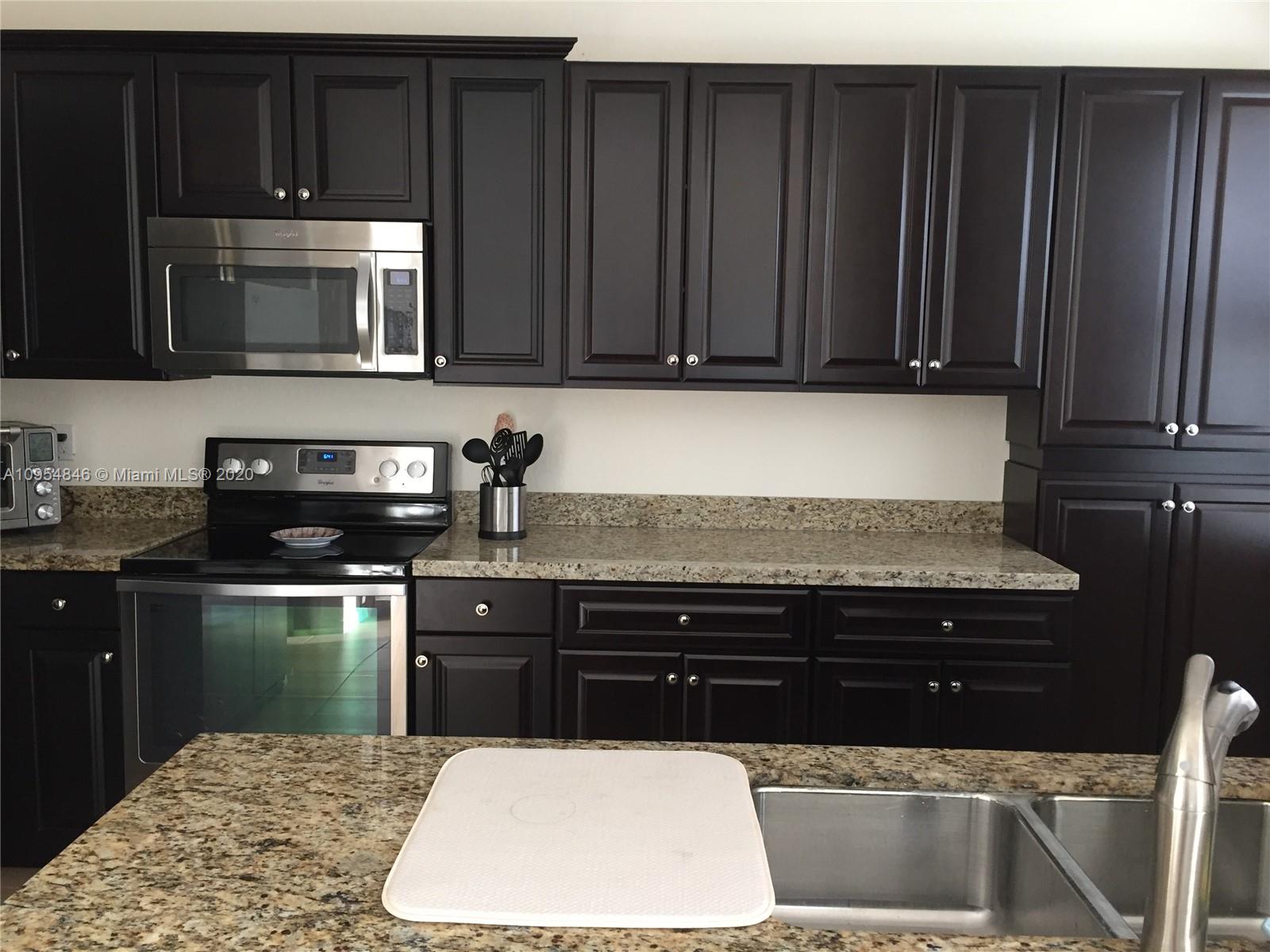 2851 Prospect Road, Unit 1306 Tamarac, FL 33309 - Photo 6 of 15 a kitchen with wooden cabinets and a microwave