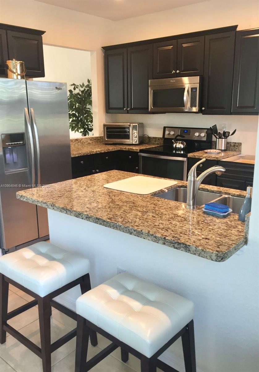 2851 Prospect Road, Unit 1306 Tamarac, FL 33309 - Photo 7 of 15 a kitchen with stainless steel appliances granite countertop a sink refrigerator and microwave