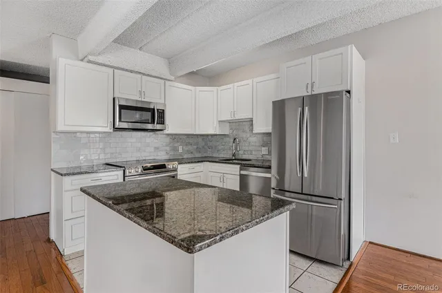 a kitchen with stainless steel appliances granite countertop a refrigerator a sink a stove a microwave and island