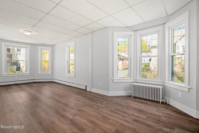 a view of an empty room with a window and wooden floor