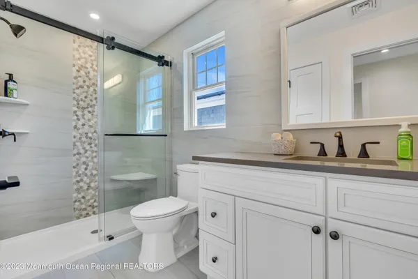 a bathroom with a granite countertop sink toilet and shower