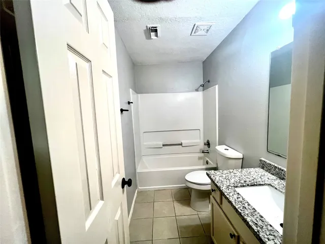 a bathroom with a granite countertop sink a toilet and shower