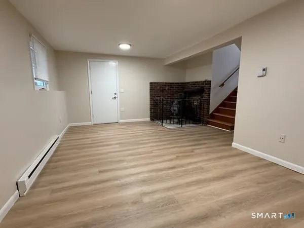 a view of an empty room with wooden floor and stairs