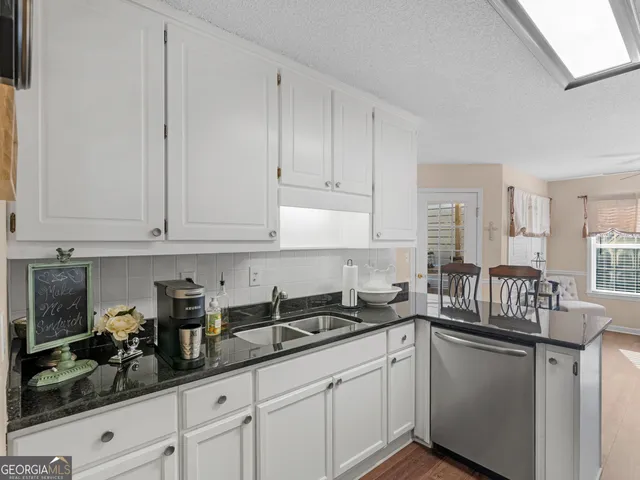 a kitchen with granite countertop white cabinets and sink