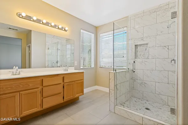 a bathroom with a granite countertop sink a mirror and a shower