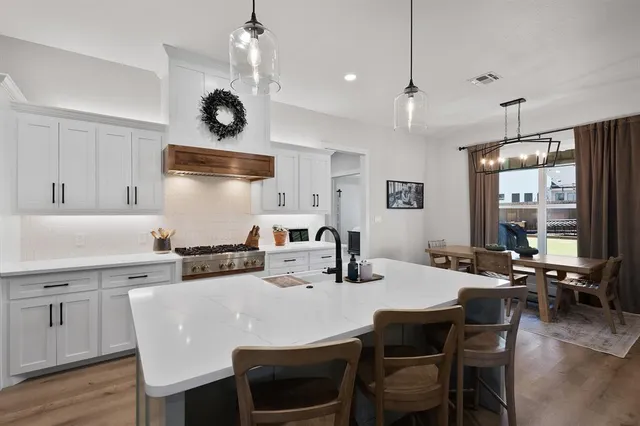 a kitchen with stainless steel appliances a dining table chairs stove and refrigerator