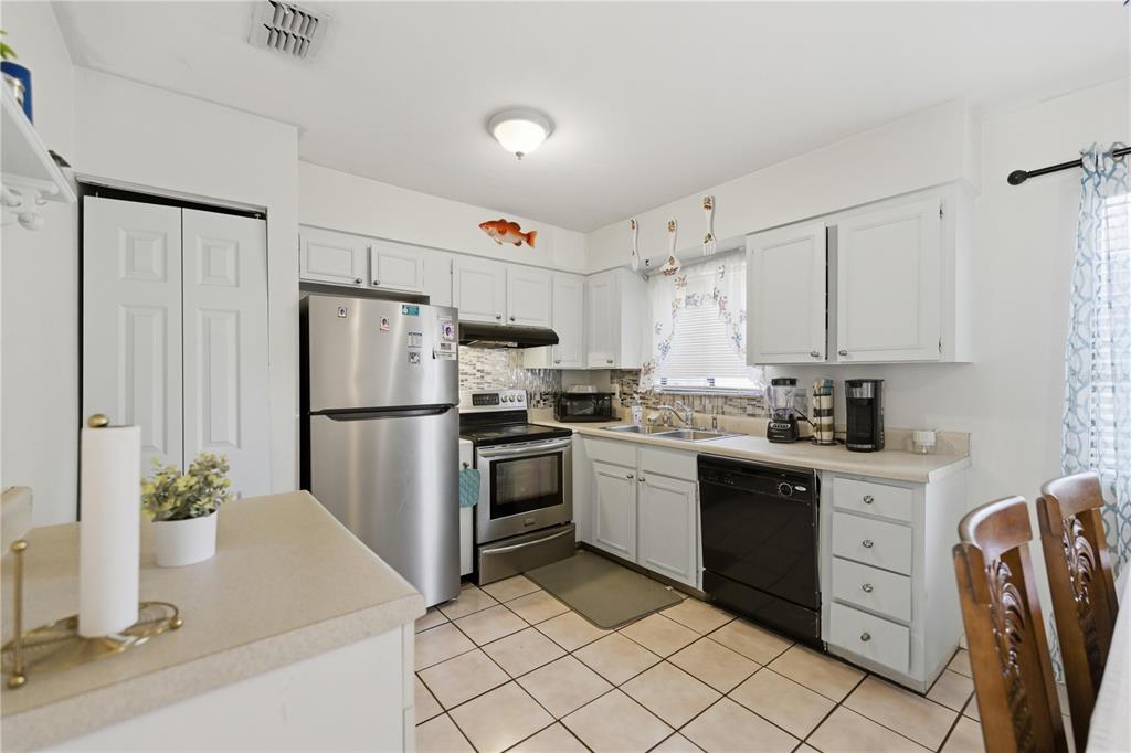 1939 Southwest 73rd Terrace Gainesville, FL 32607 - Photo 11 of 26 a kitchen with a refrigerator sink and white cabinets