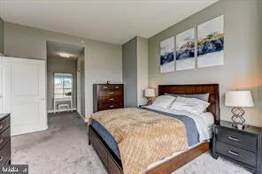 a spacious bedroom with a bed and a lamp on dresser