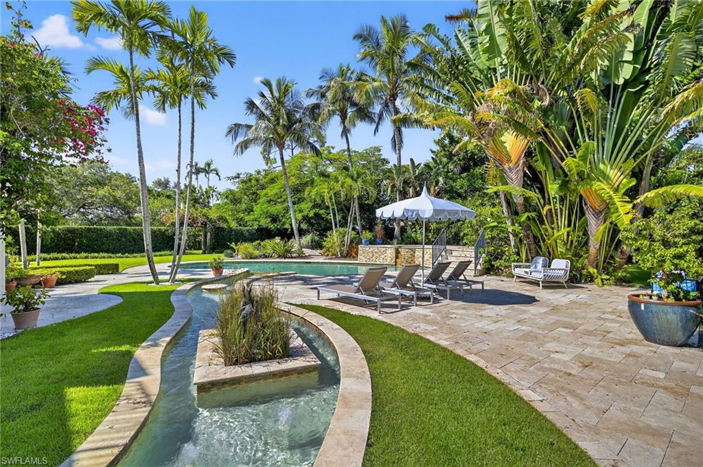 111 Caribbean Road Naples, FL 34108 - Photo 2 of 50 a view of a swimming pool with a table and chairs under an umbrella