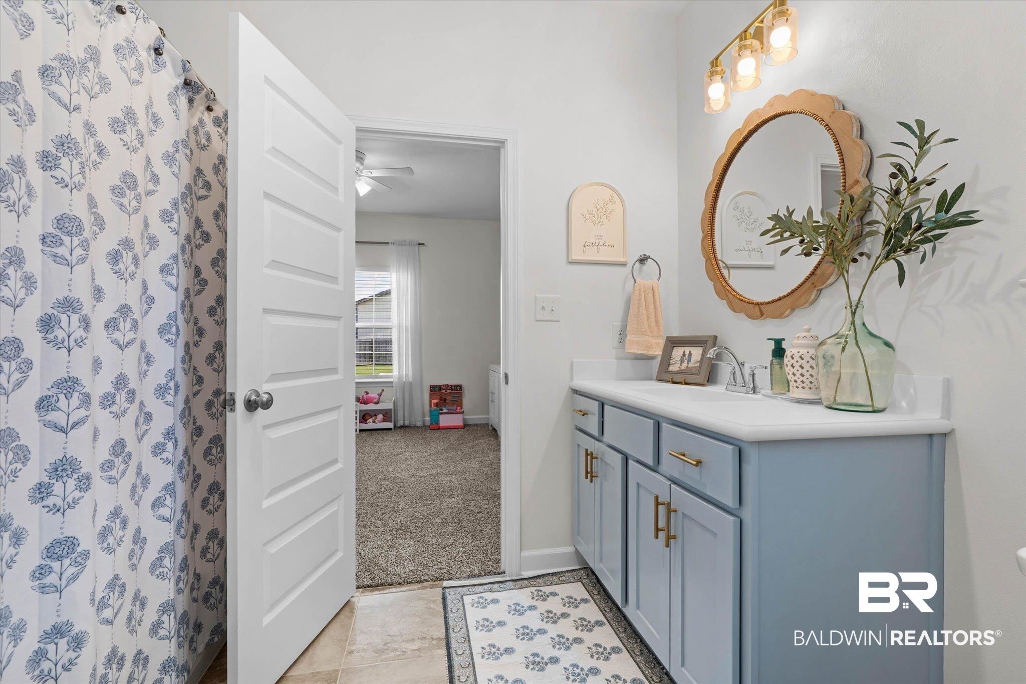 9074 Moses Way Theodore, AL 36582 - Photo 35 of 52 Bathroom featuring a single vanity with a light blue cabinet and gold hardware, a white countertop, and an oval mirror with a decorative frame
