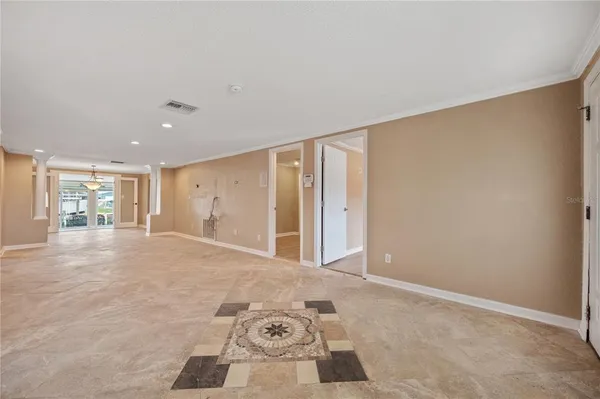a view of an empty room with wooden floor and a ceiling fan