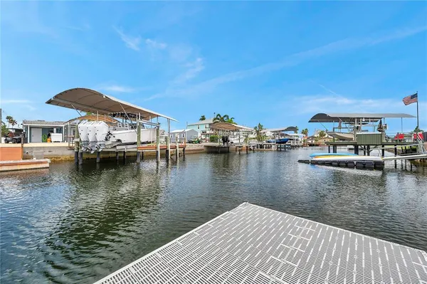 a large kitchen with granite countertop a stove top oven a sink dishwasher a refrigerator and white cabinets with wooden floor