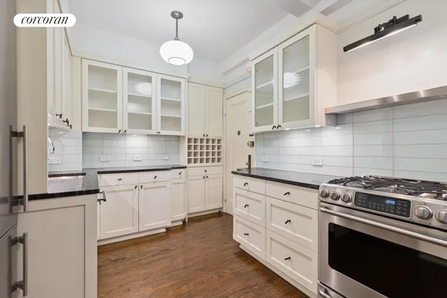 a kitchen with granite countertop white cabinets stainless steel appliances and a counter space