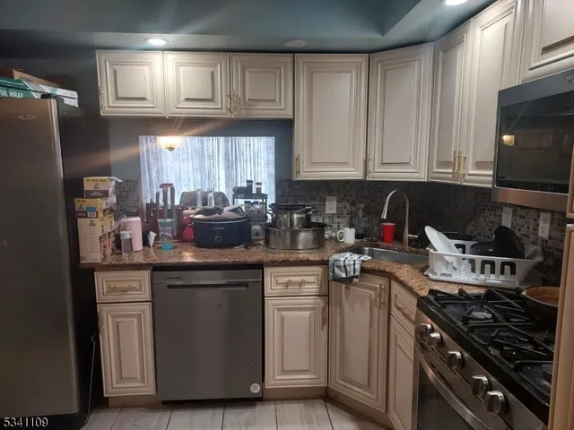a kitchen with stainless steel appliances granite countertop a stove a sink dishwasher and a refrigerator