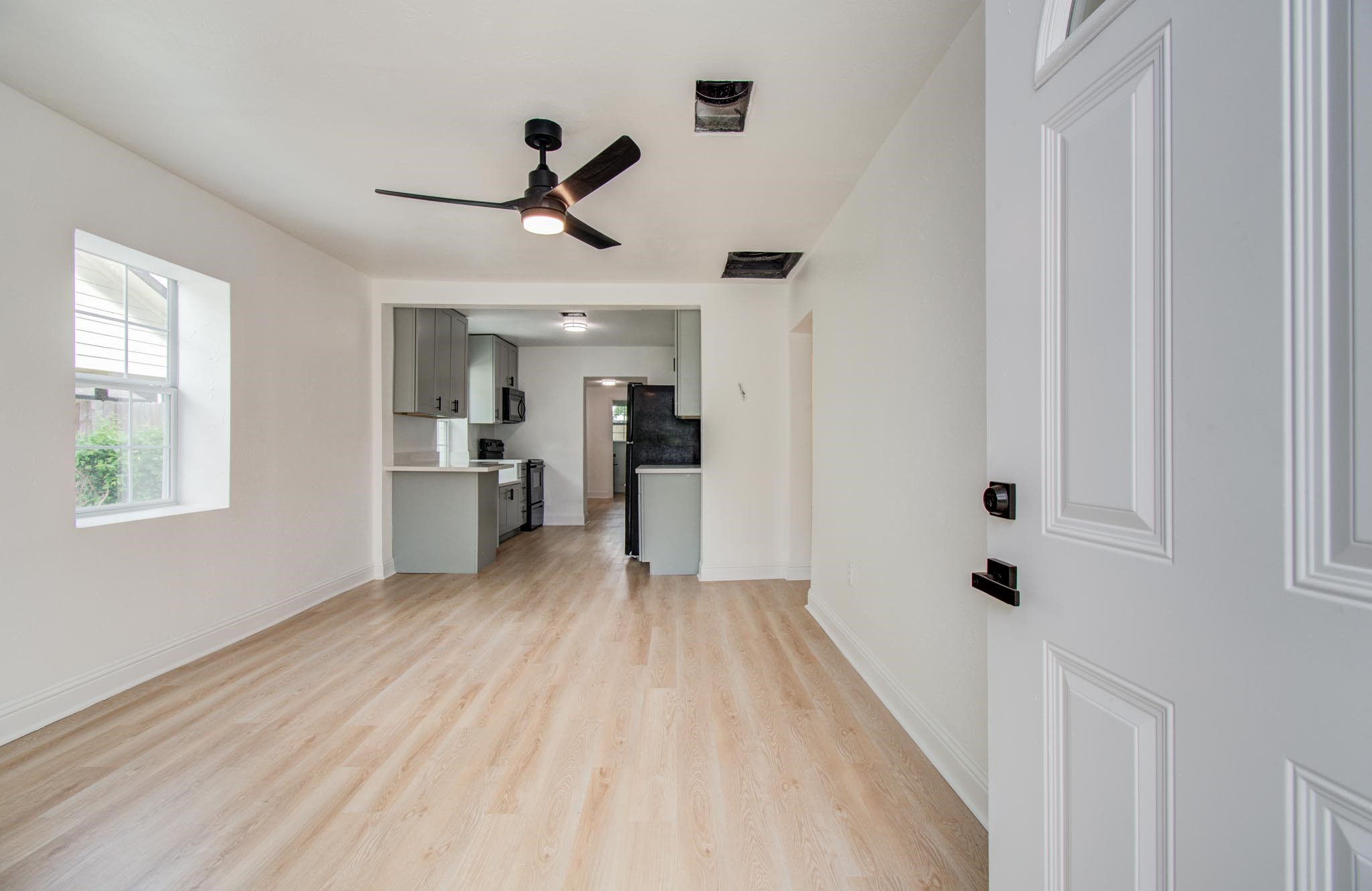 10309 Wiggins Street Houston, TX 77029 - Photo 4 of 32 a view of a kitchen with wooden floor a ceiling fan and windows